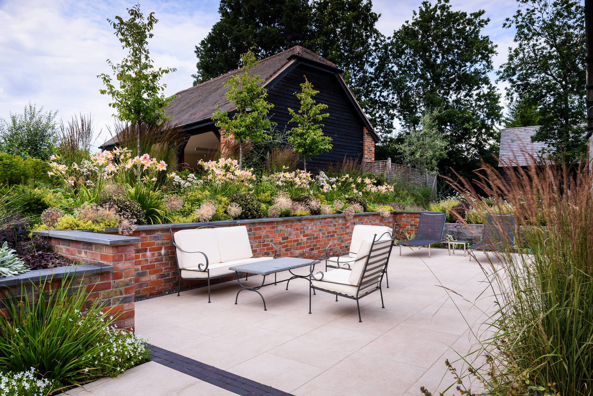 Porcelain paved terrace with brick retaining walls and slate coping
