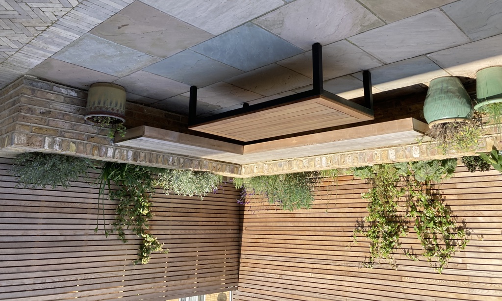 Built-in 'floating' cedar corner bench with brick raised planting border behind