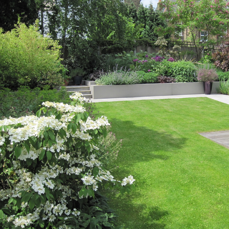 Terraced rear border beyond lawn with deep layered planting